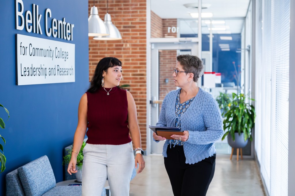 An image of Dr. AJ Jaeger walking in the hallways of the Belk Center with a colleague.